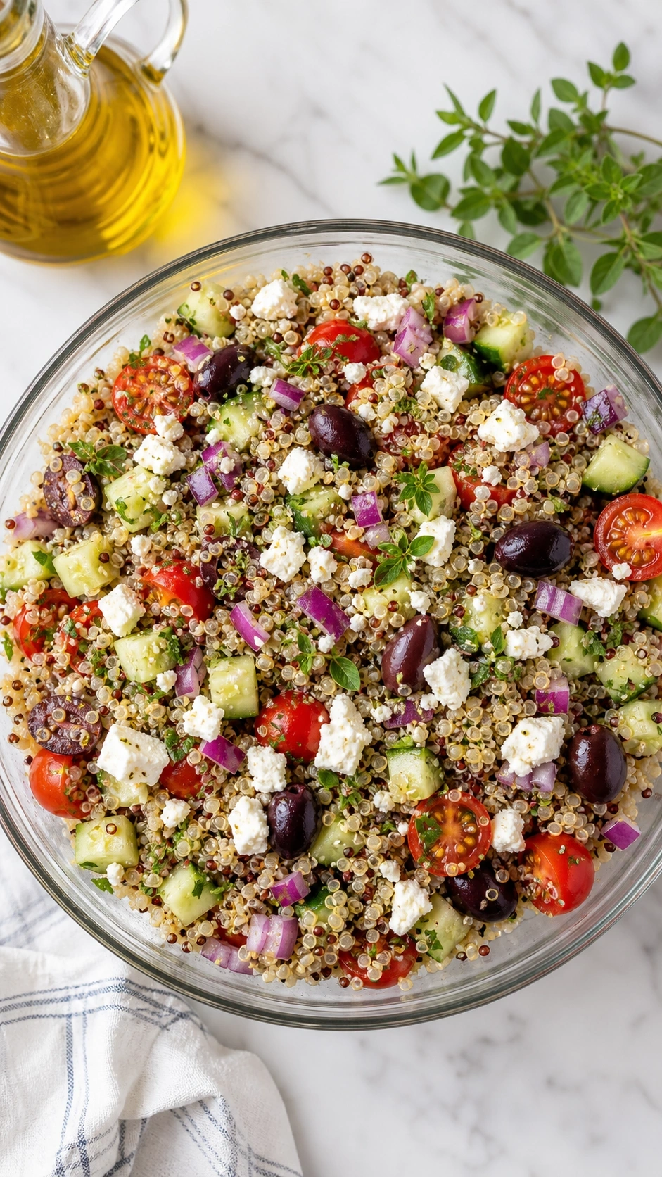 Healthy Mediterranean Quinoa Salad With Feta, Olives, And Cherry Tomatoes In A Glass Bowl On A Marble Counter.