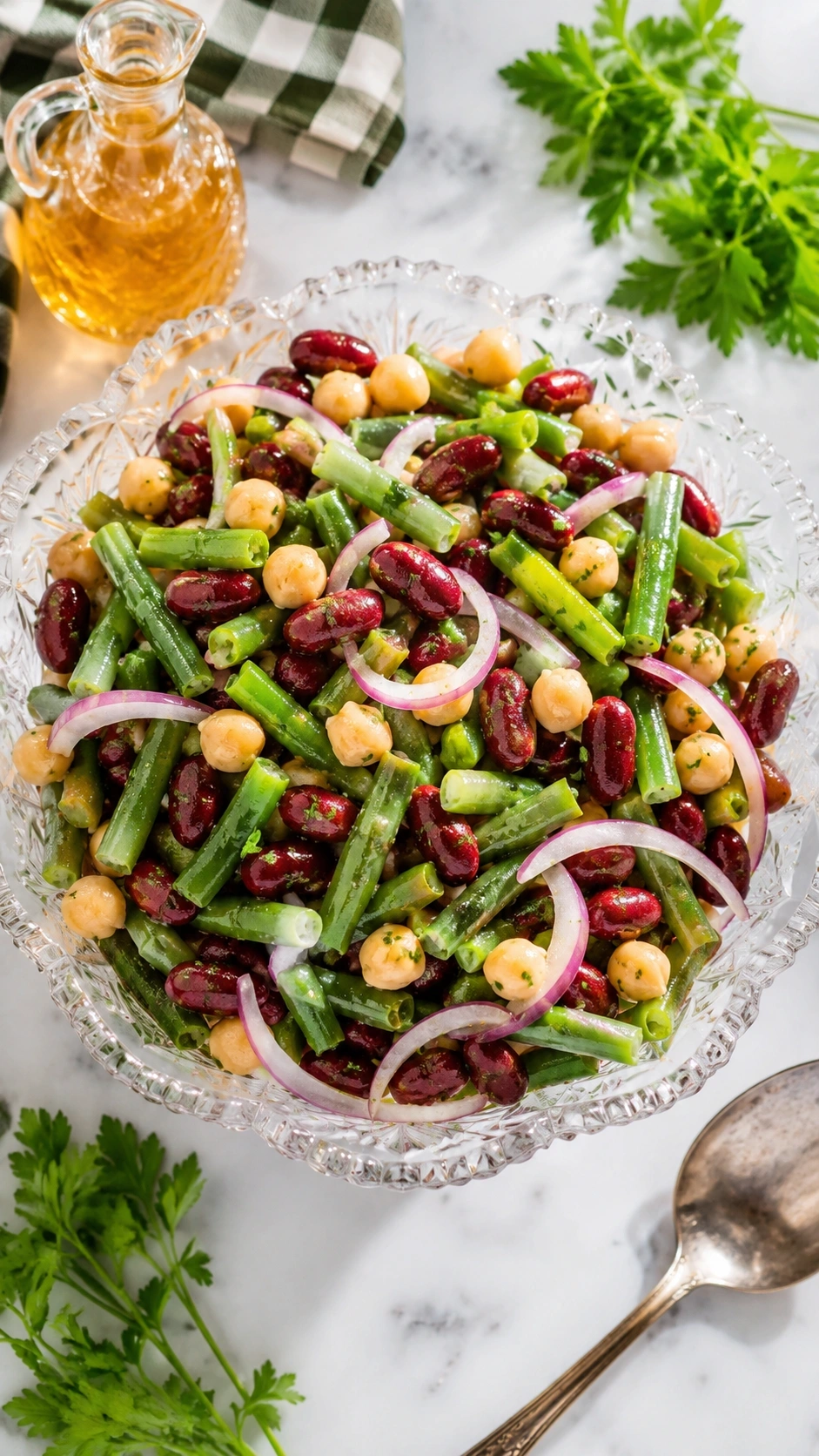 Classic three bean salad with green beans and kidney beans in a vintage glass bowl on a white marble counter.